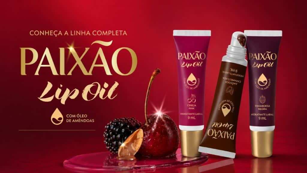 Paixão Lip Oil: linha com 3 fragrâncias e acabamento brilhante Anúncio da linha Paixão Lip Oil com três fragrâncias e acabamento brilhante, em embalagem e frascos no fundo vermelho