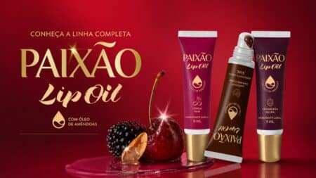 Paixão Lip Oil: linha com 3 fragrâncias e acabamento brilhante Anúncio da linha Paixão Lip Oil com três fragrâncias e acabamento brilhante, em embalagem e frascos no fundo vermelho