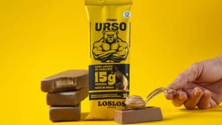 Picolé proteico Urso Chocolate com Amendoim Los Los Cimed Embalagem de picolé proteico Urso Chocolate com Amendoim Los Los Cimed com picolés de chocolate ao fundo.