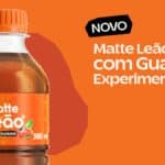 Garrafa de Matte Leão com Guaraná com rótulo “matte leão” e selo “300 ml”, com mensagem “NOVO” ao fundo.