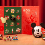 Decoração de Natal com Mickey e amigos, enfeites e caixas temáticas em fundo vermelho, sobre mesa com doces e glass pot.