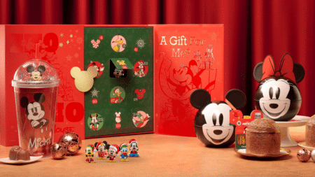 Natal com Mickey e amigos: enfeites, presentes e doces Decoração de Natal com Mickey e amigos, enfeites e caixas temáticas em fundo vermelho, sobre mesa com doces e glass pot.
