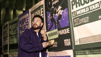 Homem em palco segurando papel ao lado de banners com a marca Nubank Parque, durante evento do Purple Project World Tour.