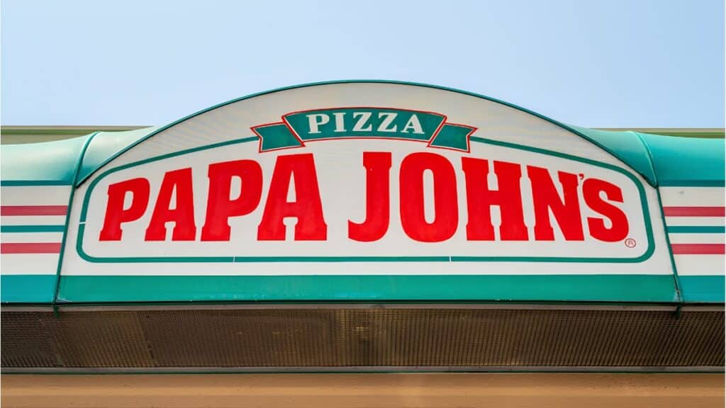 Fachada da loja com o letreiro “PAPA JOHNS” e o nome PIZZA em destaque.