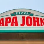 Fachada da loja com o letreiro “PAPA JOHNS” e o nome PIZZA em destaque.