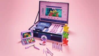 Kit de maquiagem da Martine Cosmetics com paleta e acessórios temáticos de Três Espiãs Demais em cores roxas e rosa.