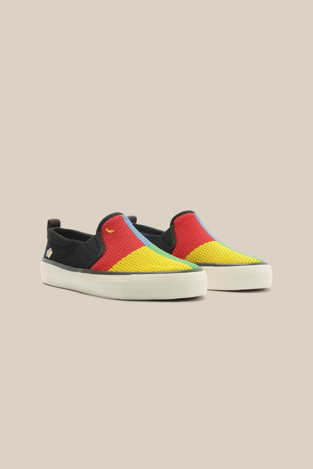 Tênis casual multicolorido estilo UNO, com partes vermelha, amarela e verde e solado branco, em fundo claro