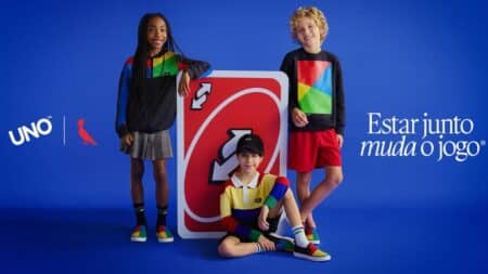 UNO Reserva: coleção com inspiração no jogo para crianças Crianças com roupas da coleção UNO da Reserva, com cartaz do jogo e crianças posando em fundo azul