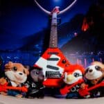 Pelúcias colecionáveis do Venancio em frente a um modelo de guitarra do Rock in Rio 2026, nas lojas da rede.
