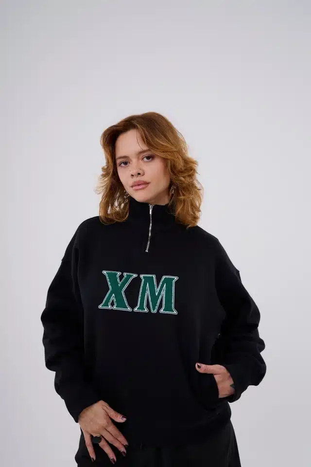 Modelo vestindo moletom preto da coleção Xeque Mate com logo XM em destaque no peito