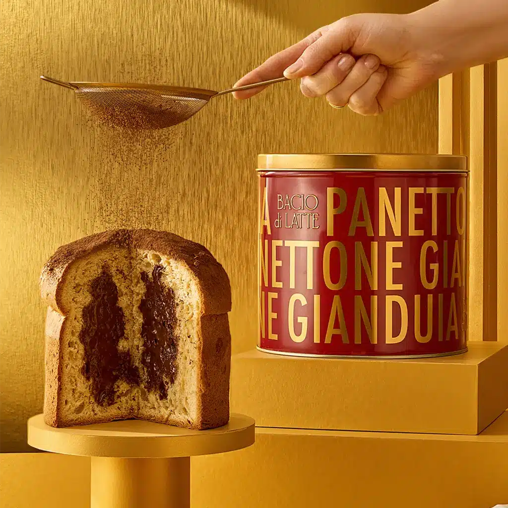 Panettone com recheio escuro servido ao lado de pote da Bacio di Latte, em cenário dourado de Natal