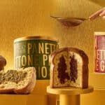 Potes e fatias de panettone Bacio di Latte com embalagens de Pistacchio e Gianduia em fundo dourado