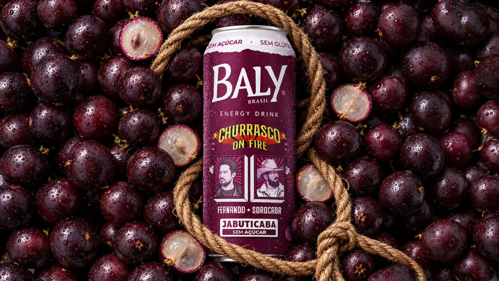 Baly Jabuticaba energético com rótulo e jabuticabas Garrafa de energético Baly Jabuticaba com corda, ao lado de jabuticabas em fundo escuro.