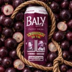 Garrafa de energético Baly Jabuticaba com corda, ao lado de jabuticabas em fundo escuro.