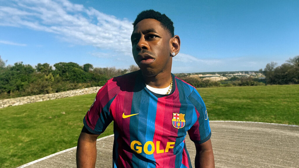 Jogador usando camisa do Barcelona multicolorida com escudo e detalhe Nike em campo ao ar livre