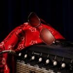 Chapéu e óculos vermelhos com estampa sobre amplificador de guitarra, na coleção Rock Fellas da Chilli Beans