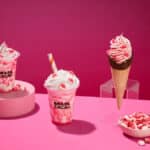 Sobremesas e chocolates da collab Fini e Brasil Cacau em fundo rosa, com copos e cone decorados com morango