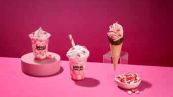 Parceria Fini e Brasil Cacau com sobremesas e chocolates Sobremesas e chocolates da collab Fini e Brasil Cacau em fundo rosa, com copos e cone decorados com morango