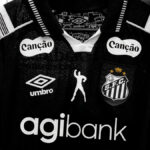 Camisa do Santos com marca Agibank e escudo do clube, em foto de estúdio sobre fundo cinza
