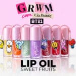 Cia Beauty BT21 Lip Oil Sweet Fruits com frascos rosa, roxos e charms colecionáveis ao fundo rosa