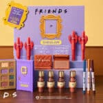 Painel promocional da coleção SHEGLAM x Friends com maquiagem, paleta de sombras, blush e batons em fundo roxo