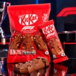 Embalagem vermelha da KitKat com carrinhos de chocolate inspirados na F1, em cenário de corrida