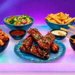 Mesa com pratos do Outbac-K inspirado na culinária sul-coreana, com frango, bolinhas apimentadas e batatas fritas.