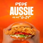 Cartaz da campanha da Aussie com hambúrguer na mão e texto “Pede Aussie” e “Se diz ‘ô-zí’”.