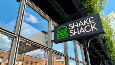 Placa da Shake Shack na fachada da loja Placa da Shake Shack na entrada de uma loja, anunciando a chegada da marca ao Brasil.