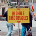 Pessoa em rua com placa “DE ONDE É ESSE SOTAQUE?” em campanha da Vitarella para o Dia do Nordestino.