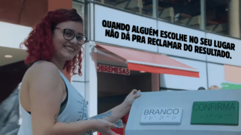 Urna “BRANCO” na campanha Whopper em Branco Pessoa em loja depositando papel na urna com o texto “BRANCO” e “CONFIRMA”, em campanha “Whopper em Branco”