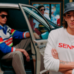 Modelo posa ao lado de carro usando boné e camiseta branca com o logo “SENN A”, em campanha inspirada em Ayrton Senna.