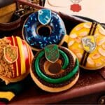 Donuts da Krispy Kreme inspirados em Harry Potter com glacês verde e azul sobre tecido temático