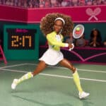 Boneca Barbie jogando tênis em quadra verde, com plateia ao fundo e raquete na mão