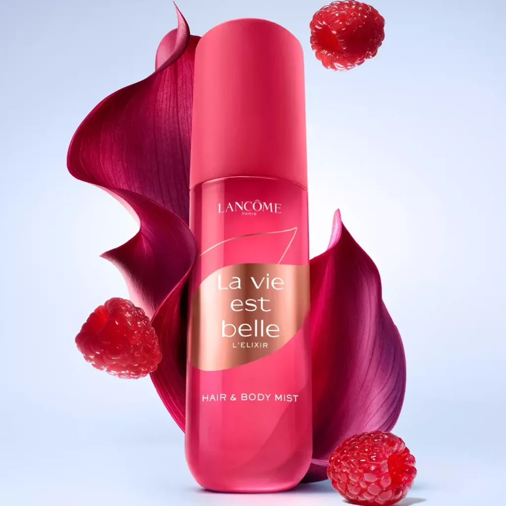 Frasco rosa de Hair & Body Mist La Vie est Belle L’Elixir, da Lancôme, com frutas vermelhas ao redor