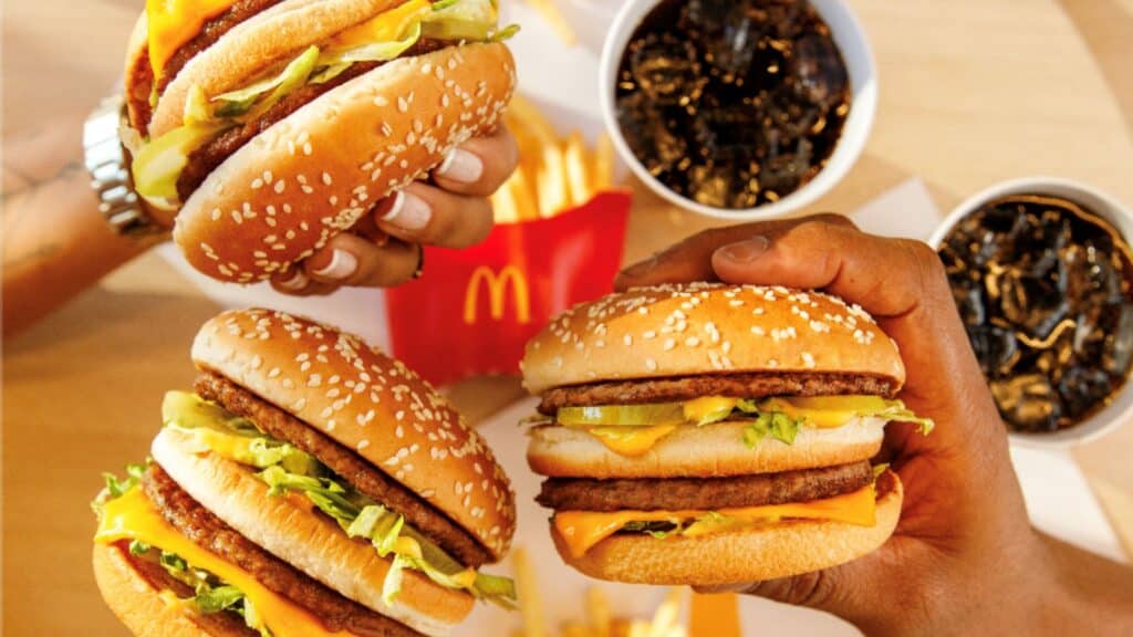 McDia Feliz 2026: hambúrgueres e arrecadação de R$ 28,5 milhões Pessoas segurando hambúrgueres do McDia Feliz 2026 em comemoração à arrecadação de R$ 28,5 milhões.