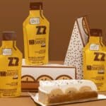 Embalagens de energy gel Nanica Z2 Performance sabor banoffee ao lado de fatia de bolo banoffee em bandeja