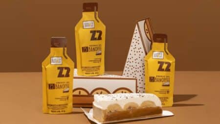 Nanica Z2 Performance energy gel banoffee Embalagens de energy gel Nanica Z2 Performance sabor banoffee ao lado de fatia de bolo banoffee em bandeja