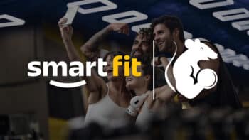 Logo Smart Fit com atleta e halter em academia Imagem com o logo Smart Fit e um ícone de halter com um atleta em academia ao fundo.