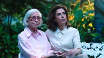 Fernanda Montenegro e Fernanda Torres no TikTok Fernanda Montenegro e Fernanda Torres sentadas juntas em campanha do TikTok, em cenário externo com flores